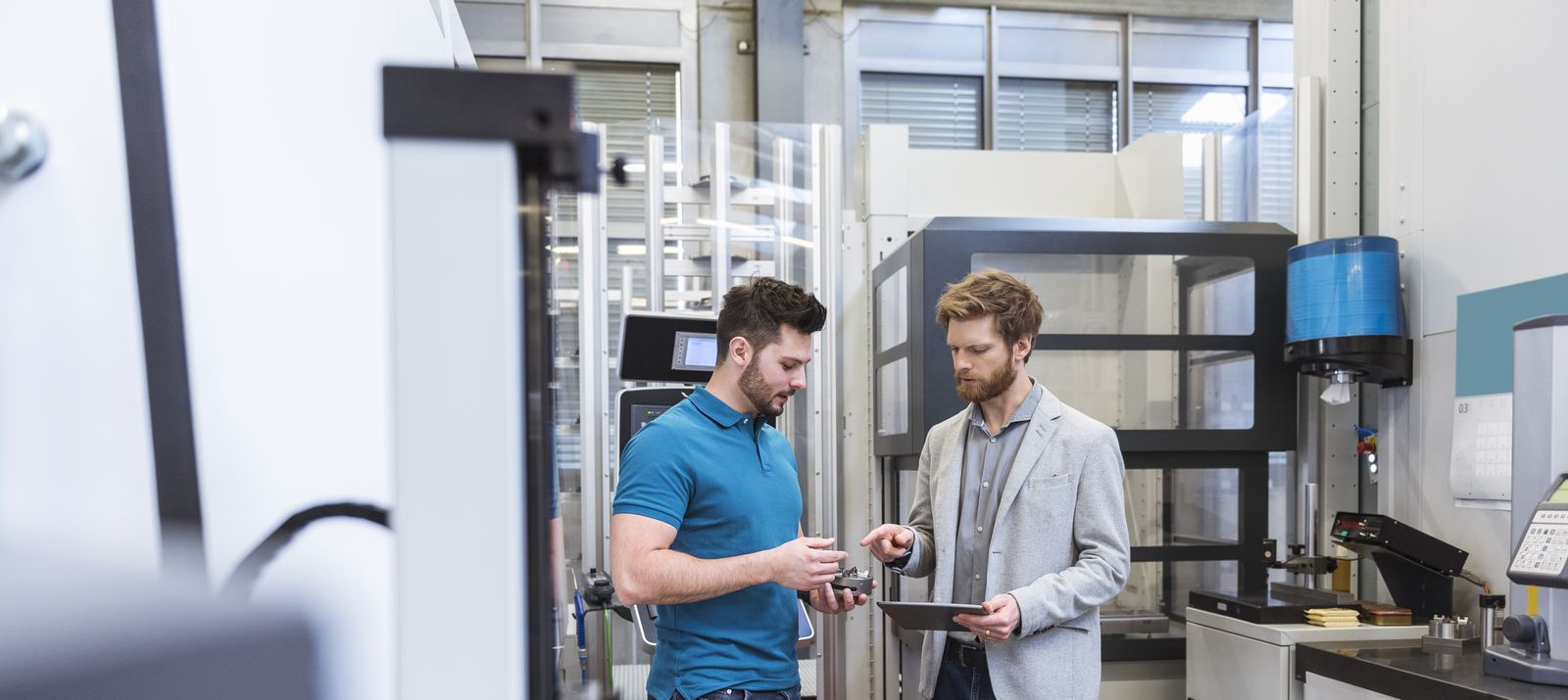 Two men with tablet talking in modern factory