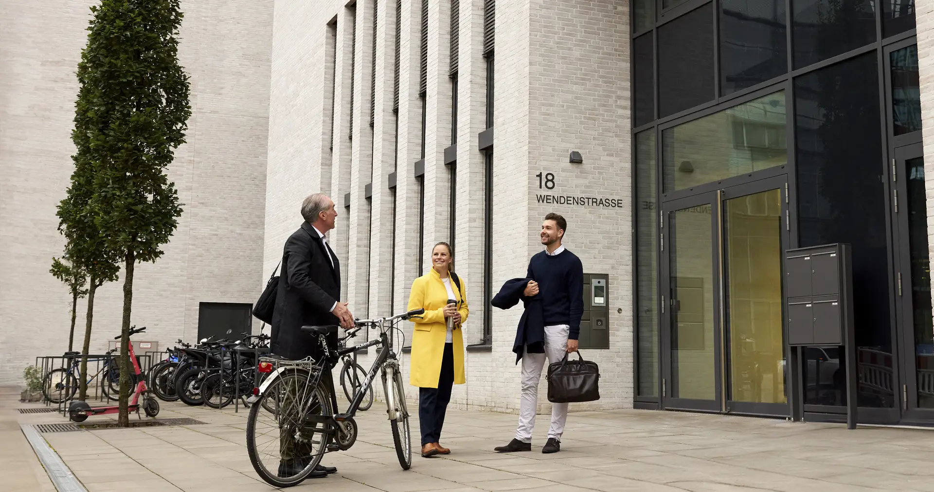 Three people in front of an office building with a bike
