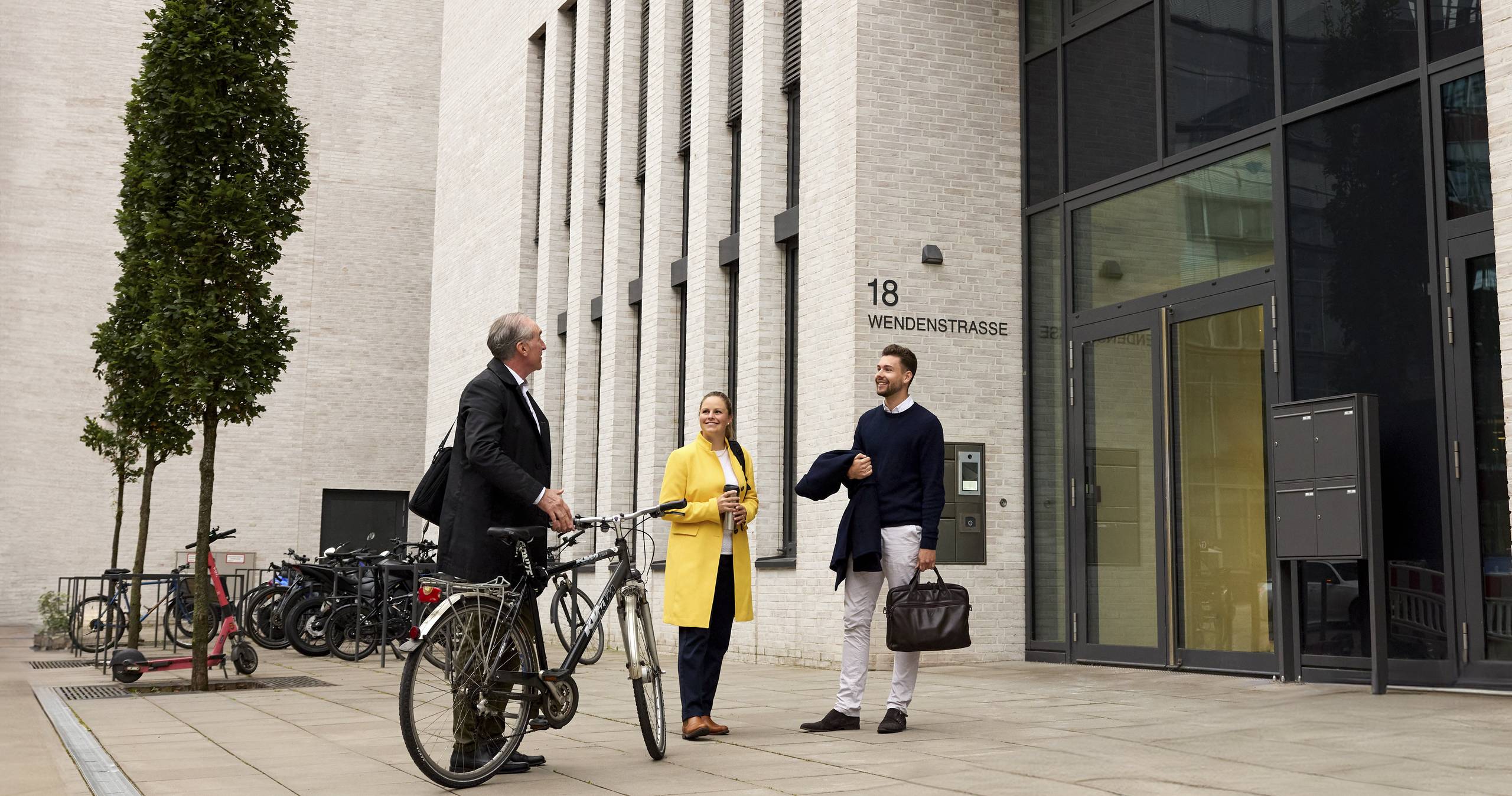 Three people in front of an office building with a bike
