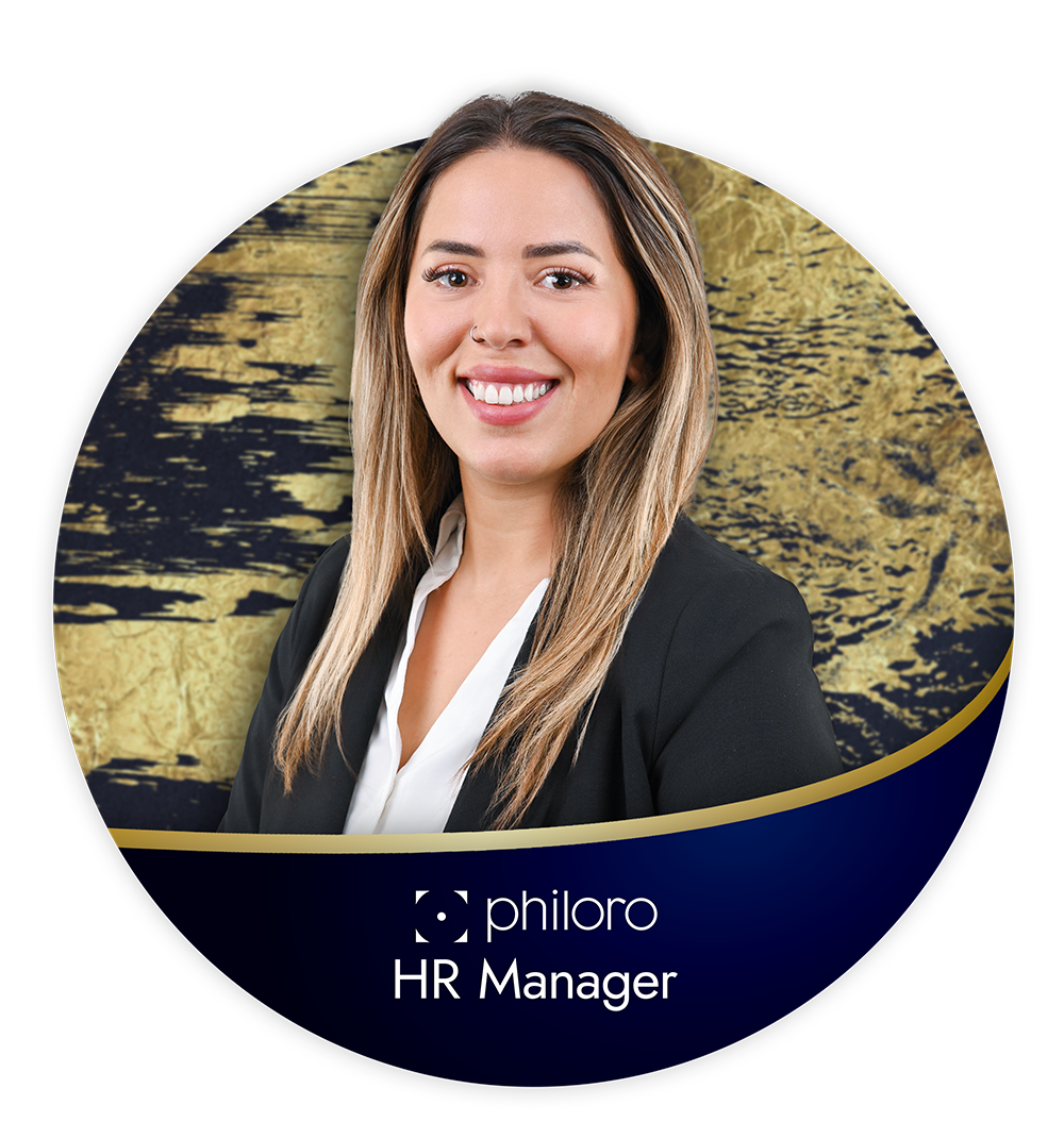 Frau mit langem Haar in schwarzem Blazer lächelt vor einem gold-blauen Hintergrund. Text: "philoro HR Manager".