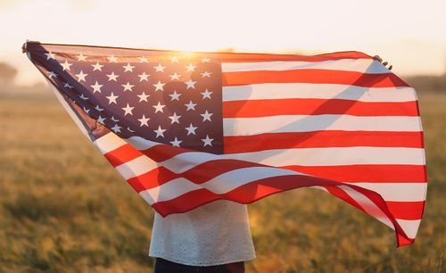 Eine Person streckt eine amerikanische Fahne hinter ihrem Rücken in die Luft.