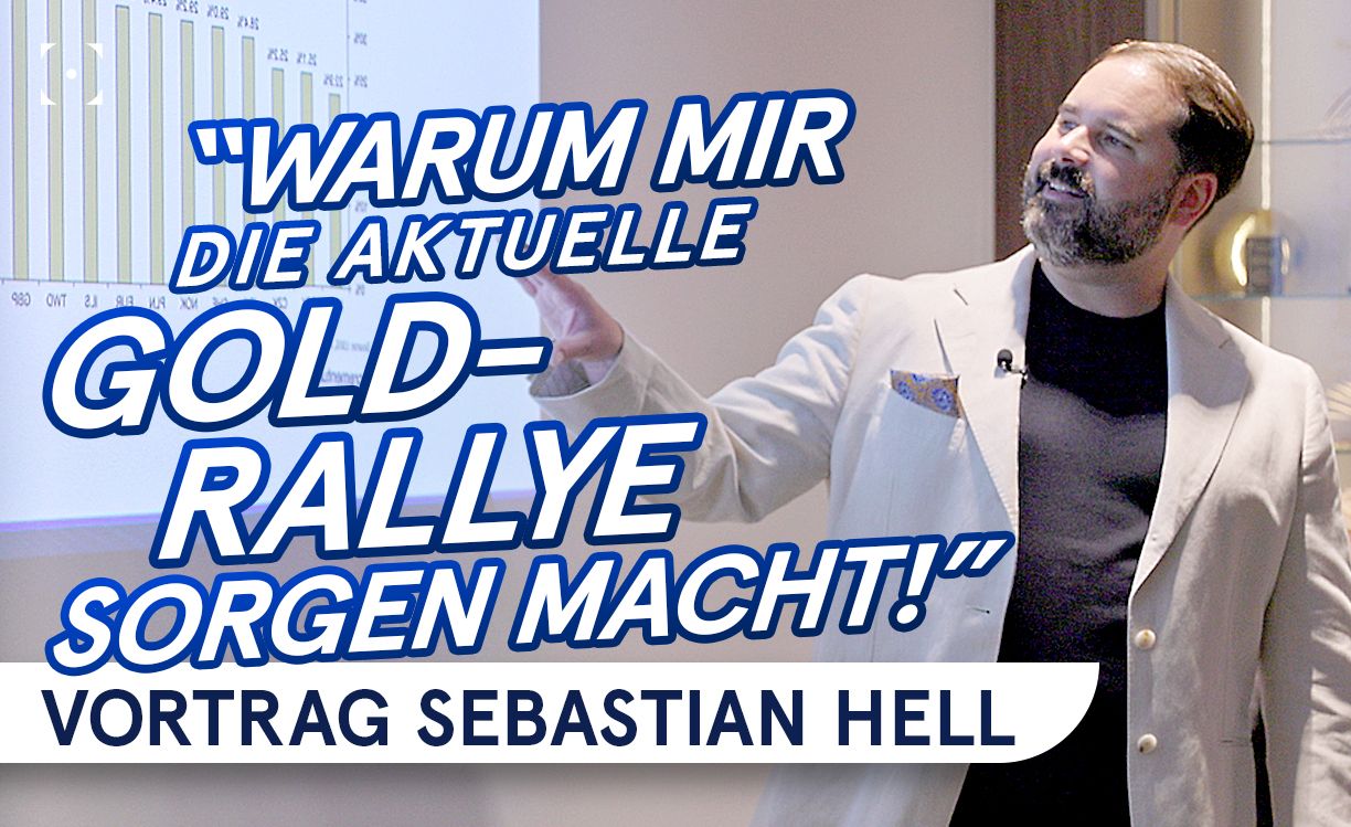 Mann in beigem Anzug gibt einen Vortrag mit dem Titel "Warum mir die aktuelle Gold-Rallye Sorgen macht!" Vor einem Diagrammhintergrund.
