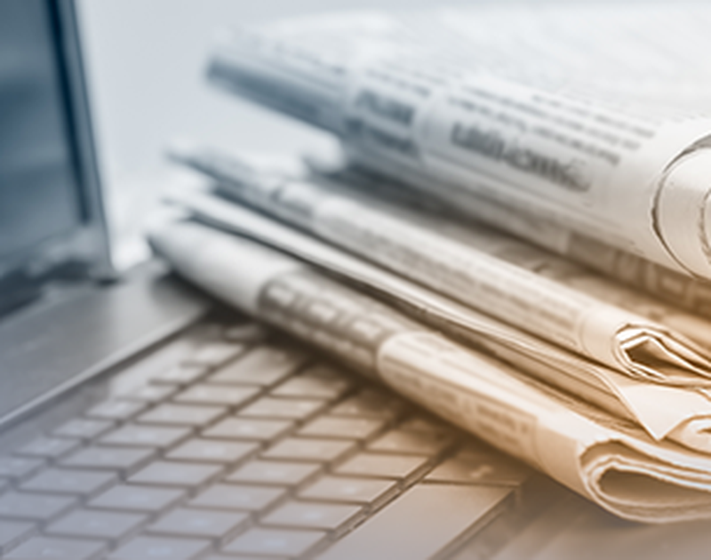 Zeitungen liegen übereinander auf einer Laptoptastatur.