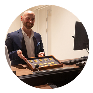 Ein Mann steht am Schalter und beratet Kund:innen zu Goldmünzen und –barren