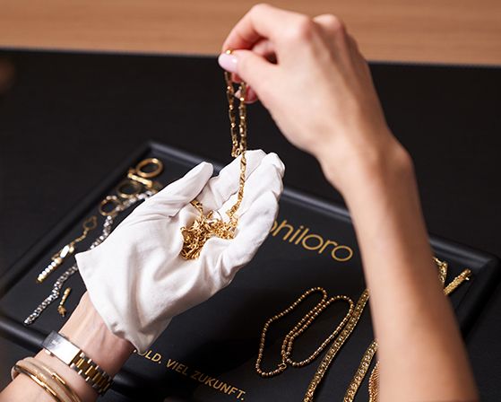 Eine Person hält eine alte Goldkette zur Bewertung in der Hand.