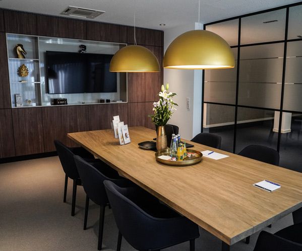 Ein Foto des edlen Beratungsraumes in der philoro Filiale in Düsseldorf mit Blick auf den edlen Besprechungstisch aus Holz und Besprechungsstühlen.