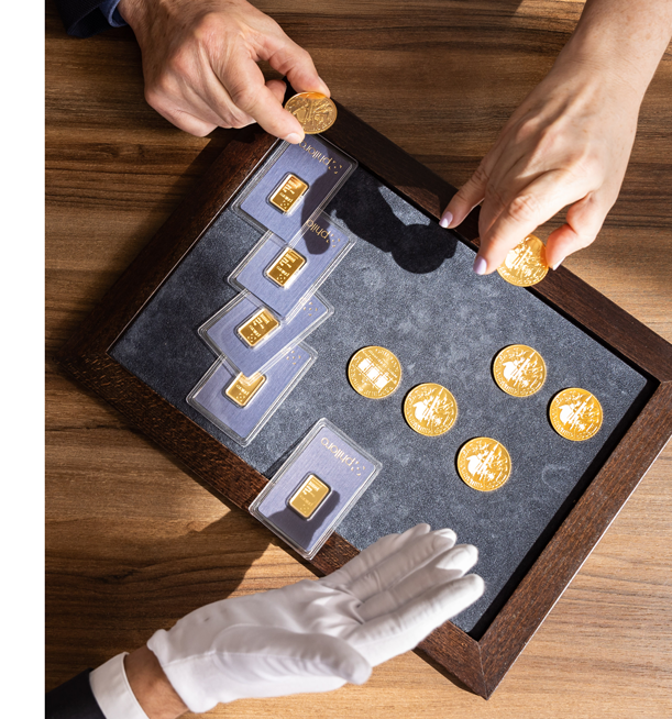 Neue Investitionen aus dem Verkauf alter Münzen Münzen und Barren liegen auf einem Tablett.