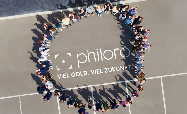 Warum philoro philoro Mitarbeiten stehen im Kreis. In der Mitte ist das philoro Logo zu sehen.