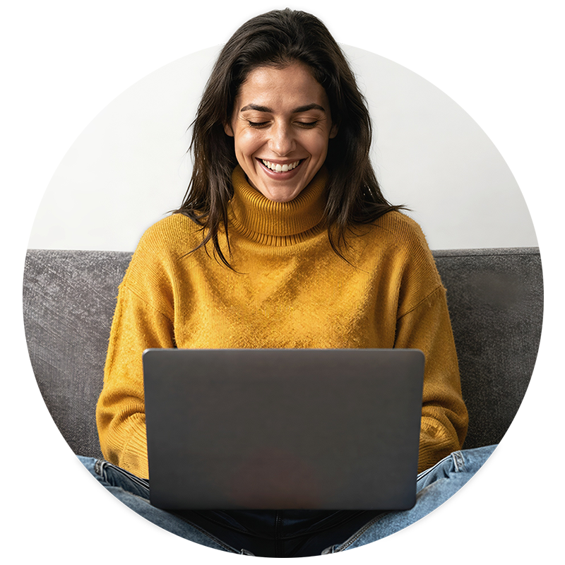 Edelmetalle Online Eine junge Frau schaut lachend auf einen Laptop - sie bestellt Edelmetalle online bei philoro.