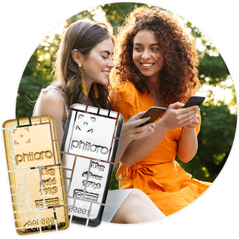 Zwei junge Mädchen schauen auf ihre Smartphones. Im Vordergund sind Gold- und Silberbarren mit philoro-Prägung.