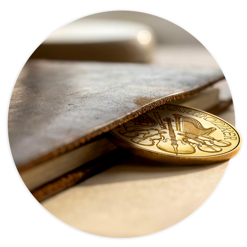 Stilles Vermögen Eine goldene Philharmoniker-Münze, die aus einem alten Lederbuch ragt.