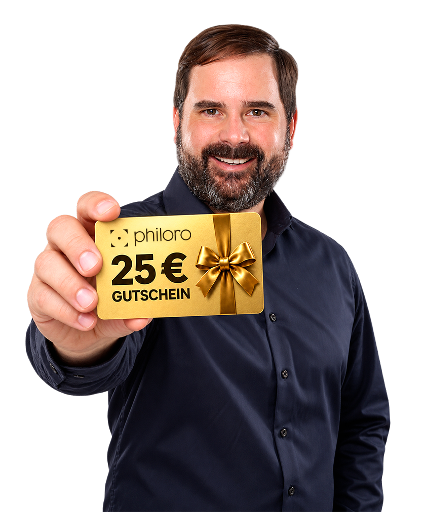 Ein lächelnder Mann in dunkelblauem Hemd hält einen goldenen philoro Gutschein im Wert von 25 € mit Schleife in der Hand.