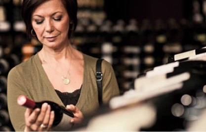 Woman in a shop looking at a wine bottle