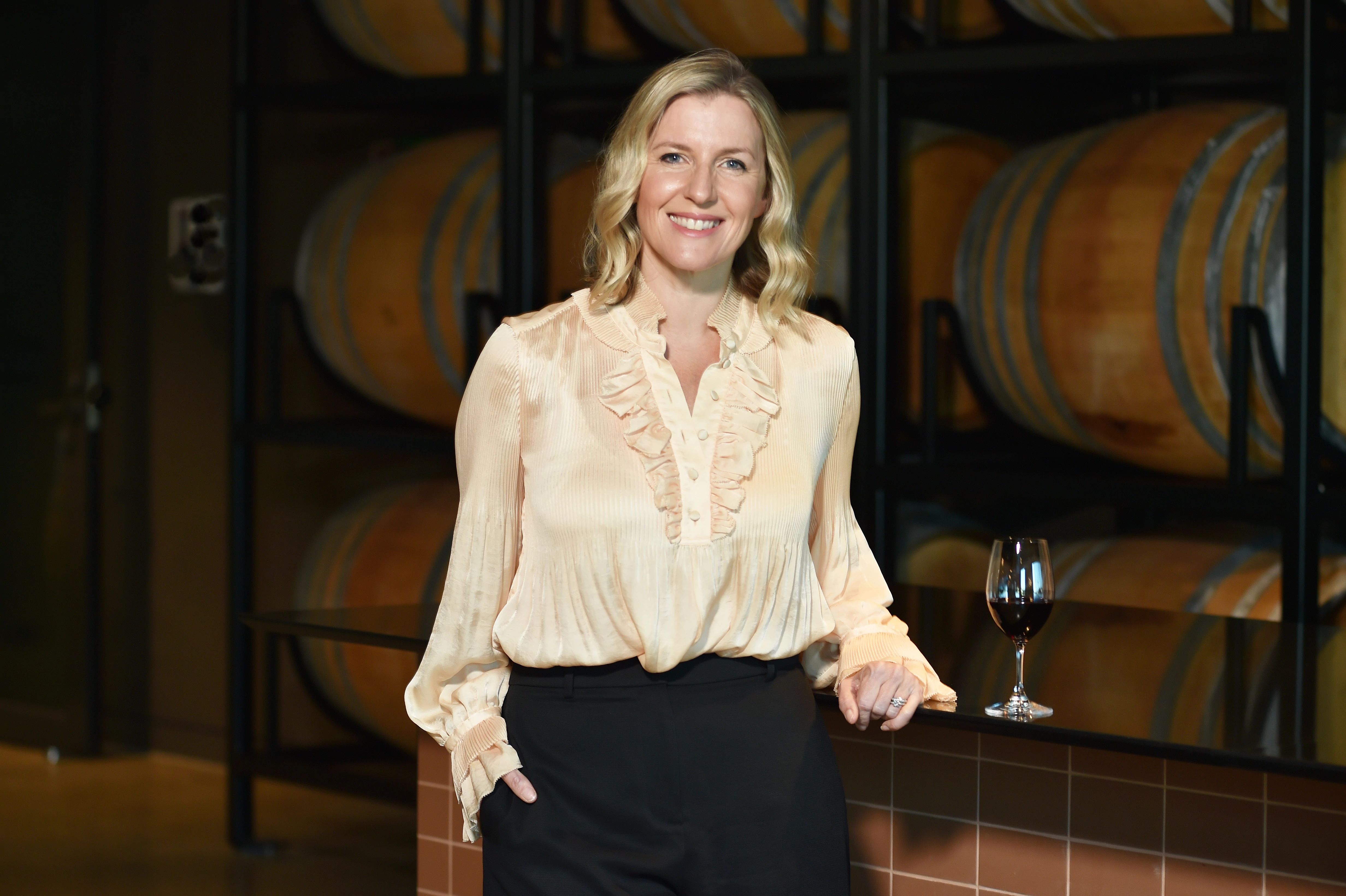 A photo of a woman standing in front a stack of wine barrels