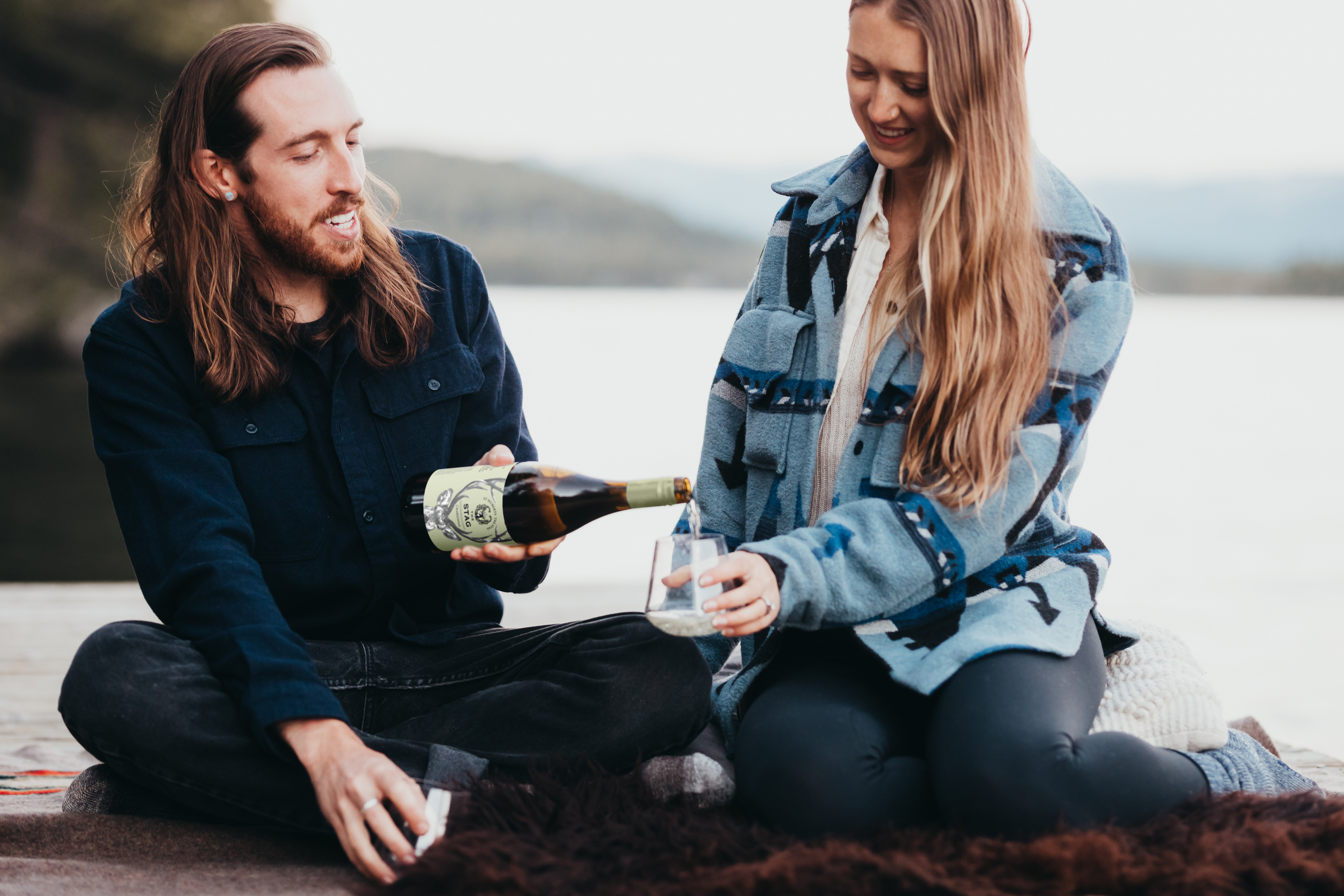 Couple pouring a glass of wine next to the lake