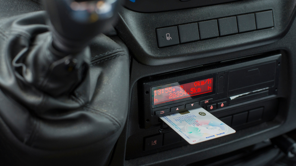 Tacógrafo digital del vehículo con tarjeta de conductor insertada, mostrando tiempos y distancias para el cumplimiento de la *tabla de sanciones tacógrafo