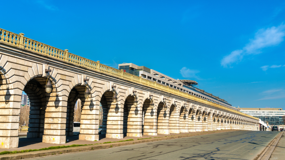Viaduc en pierre à arches sous un ciel bleu, bordant une route symbole de la transition énergétique et de l’impact du prix des biocarburants sur le transport routier.