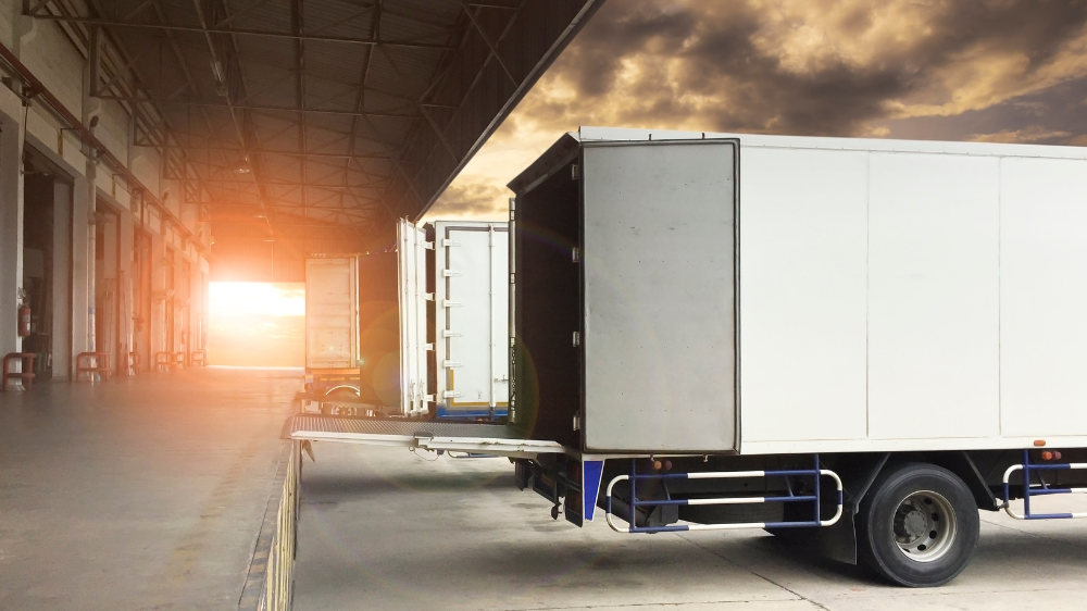 Muelle logístico al atardecer con varios camiones listos para la estiba de carga, reflejando la coordinación y el ritmo de las operaciones diarias.