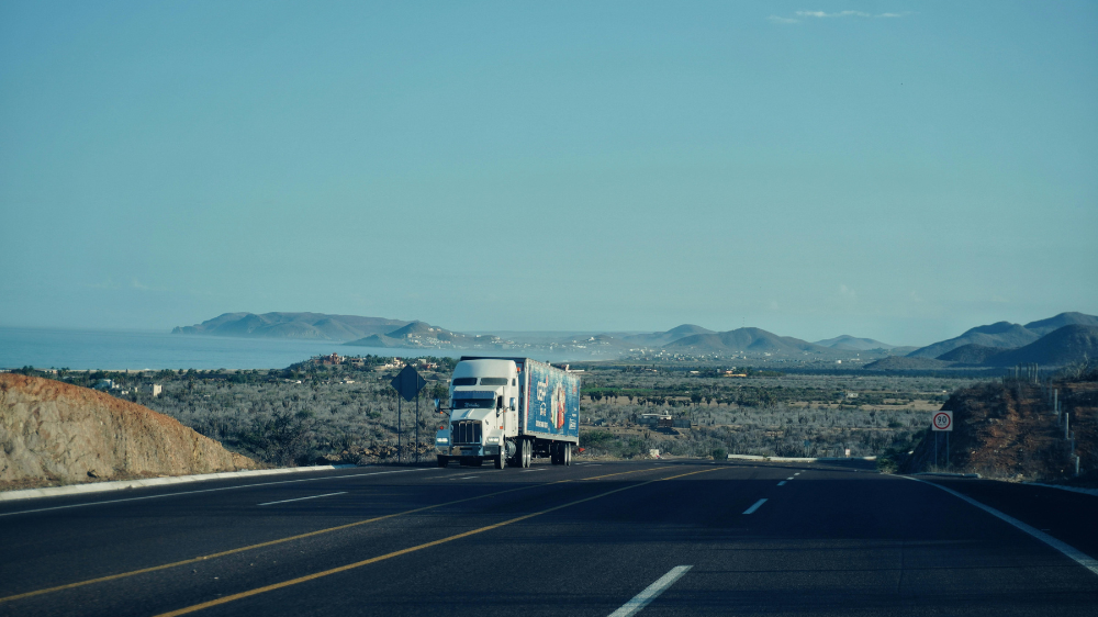 Camión de gran tonelaje circulando por una autopista costera, imagen asociada a optimizar rutas de transporte.