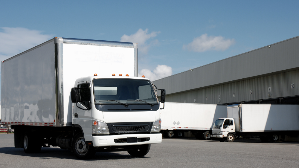 Camions de livraison d’une entreprise de transport en 2026 stationnés devant un quai de chargement