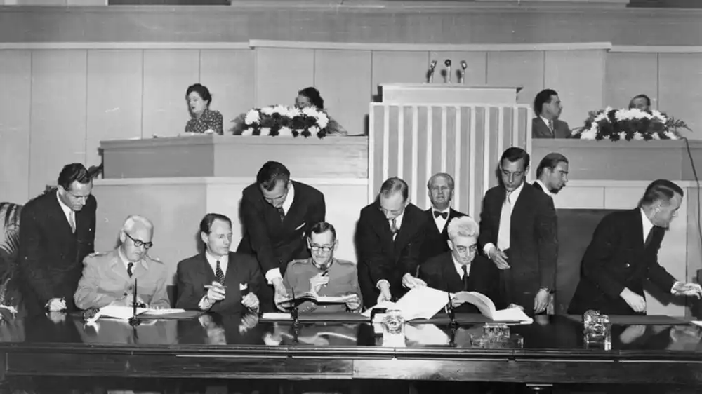 Signature officielle de la Convention de Genève avec des délégués réunis autour d’une table