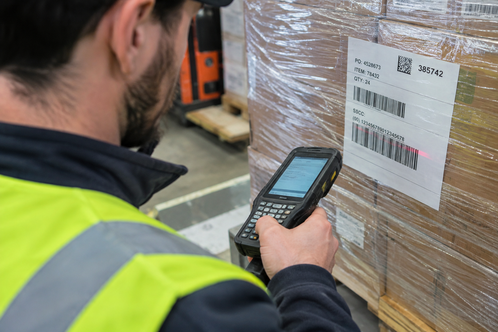 Agent logistique scannant l'étiquette de traçabilité d'une palette pour assurer le suivi d'un envoi en messagerie. 5