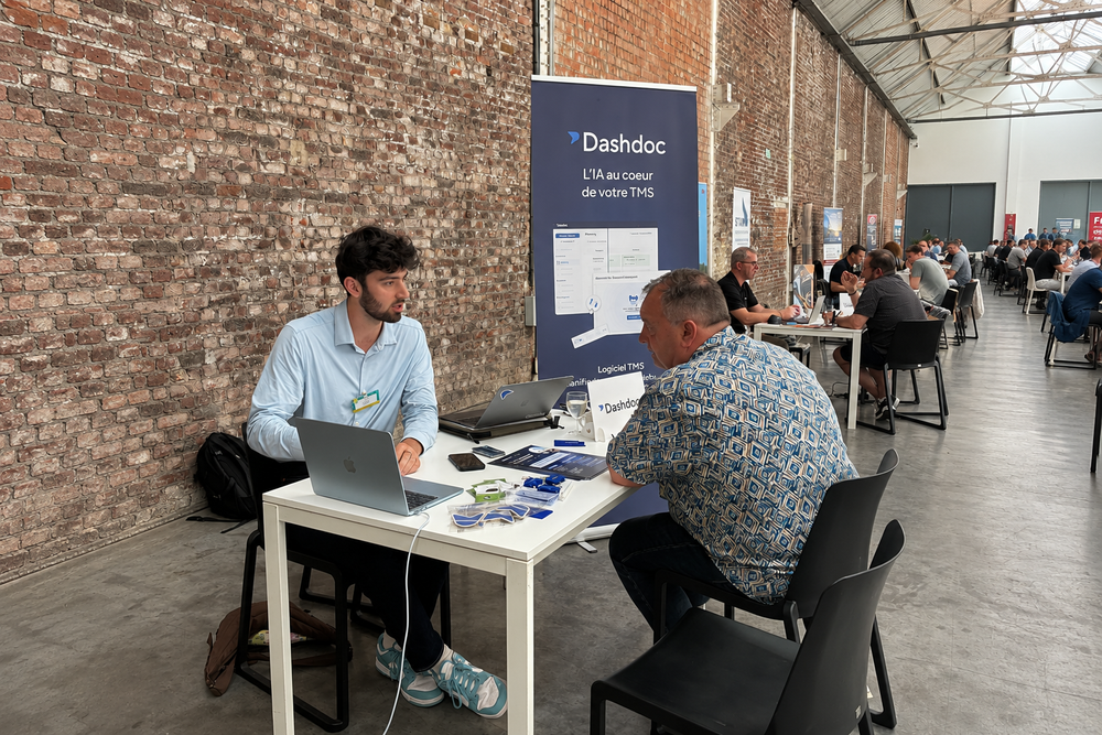 Échange autour d'un ordinateur sur le stand Dashdoc, devant le kakémono de la marque, au séminaire France Benne à Bruxelles