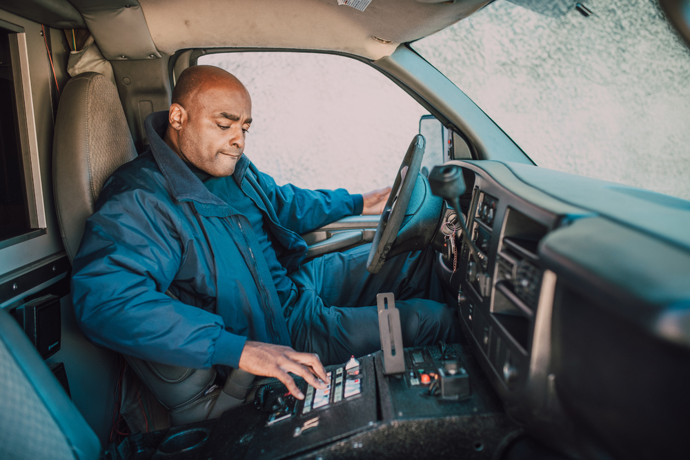 Hombre con uniforme azul operando el equipo dentro del vehículo y manejando los controles del tacógrafo.