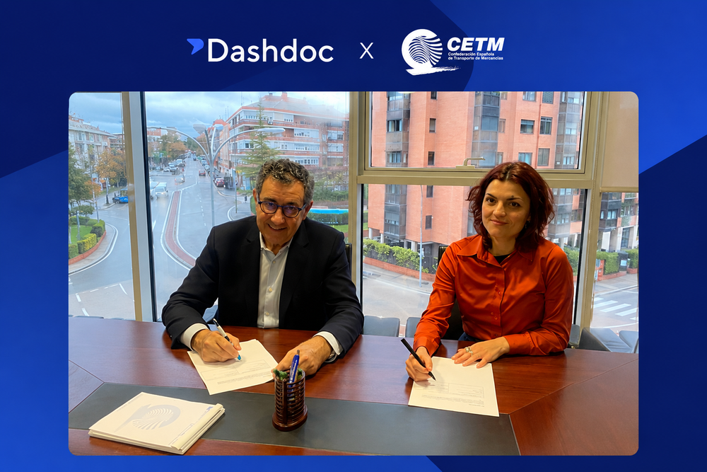 Dos representantes firman el acuerdo Dashdoc x CETM, con los logos de ambas entidades sobre la sala