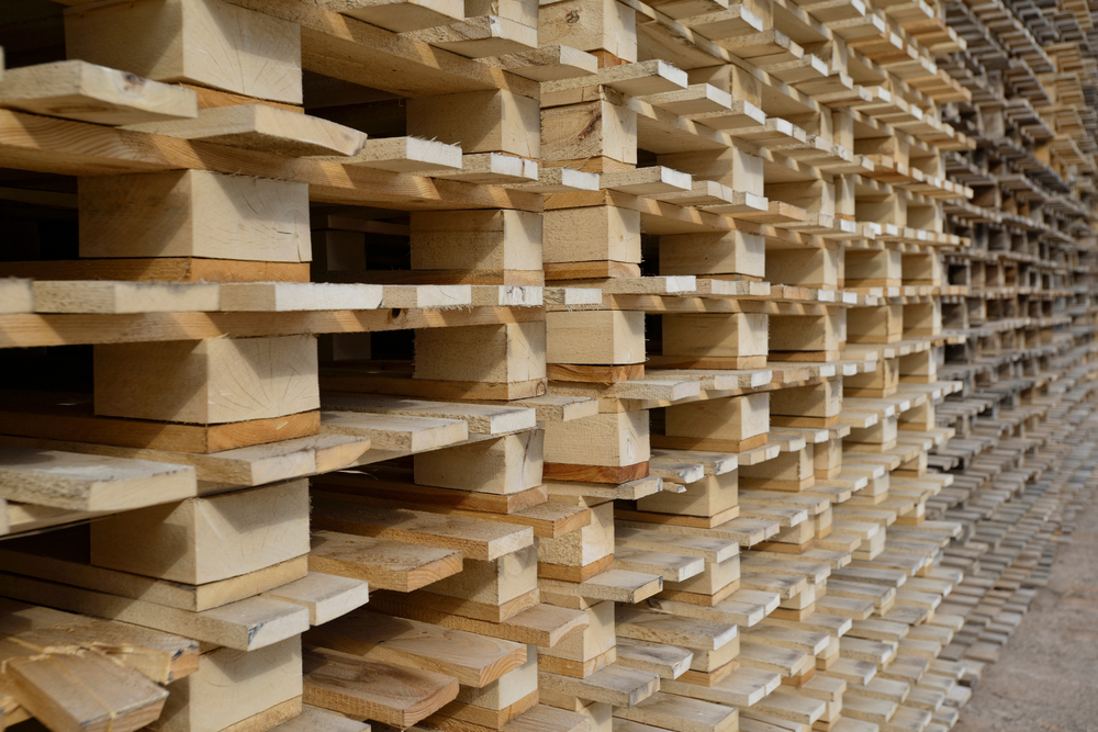 Pallets de madera apilados en un patrón denso y ordenado, con un efecto visual geométrico y repetitivo.