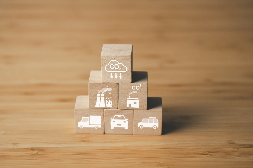 Icônes environnementales (usines, véhicules, CO2) empilées en pyramide pour illustrer les enjeux à relever pour décarboniser le transport.