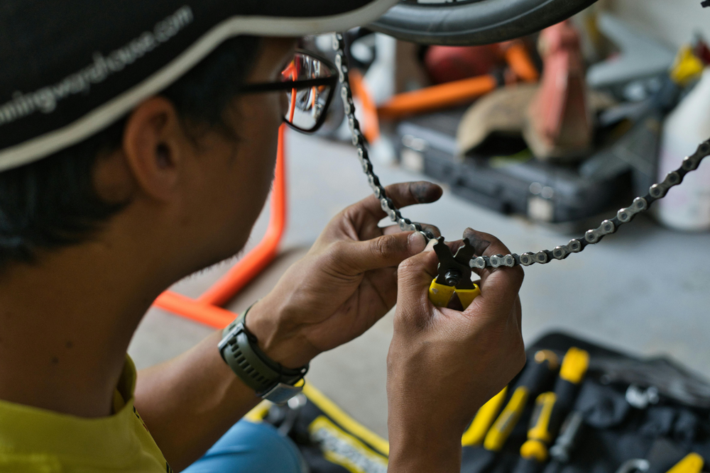 Persona utilizando una herramienta para reparar una cadena de bicicleta, metáfora visual de la supply chain y sus procesos de mantenimiento.