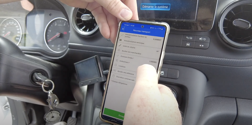 Mains tenant un smartphone dans une voiture en train de toucher le menu d une application avec le tableau de bord le volant et des clés suspendues visibles