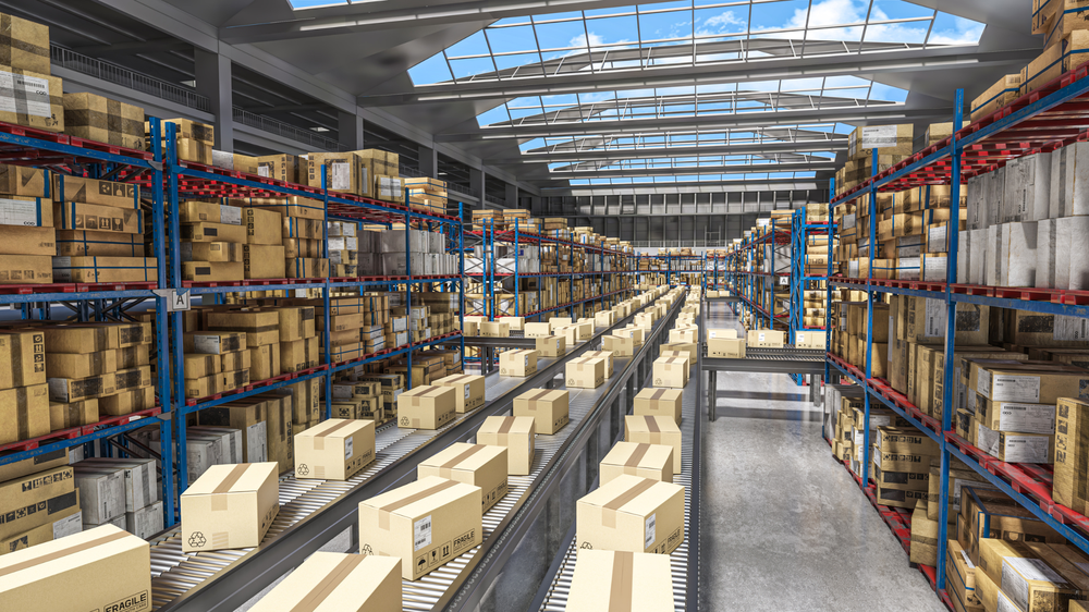 Gran almacén con filas de estanterías llenas de cajas y cintas transportadoras en funcionamiento, ilustrando la eficiencia de la externalización logística.