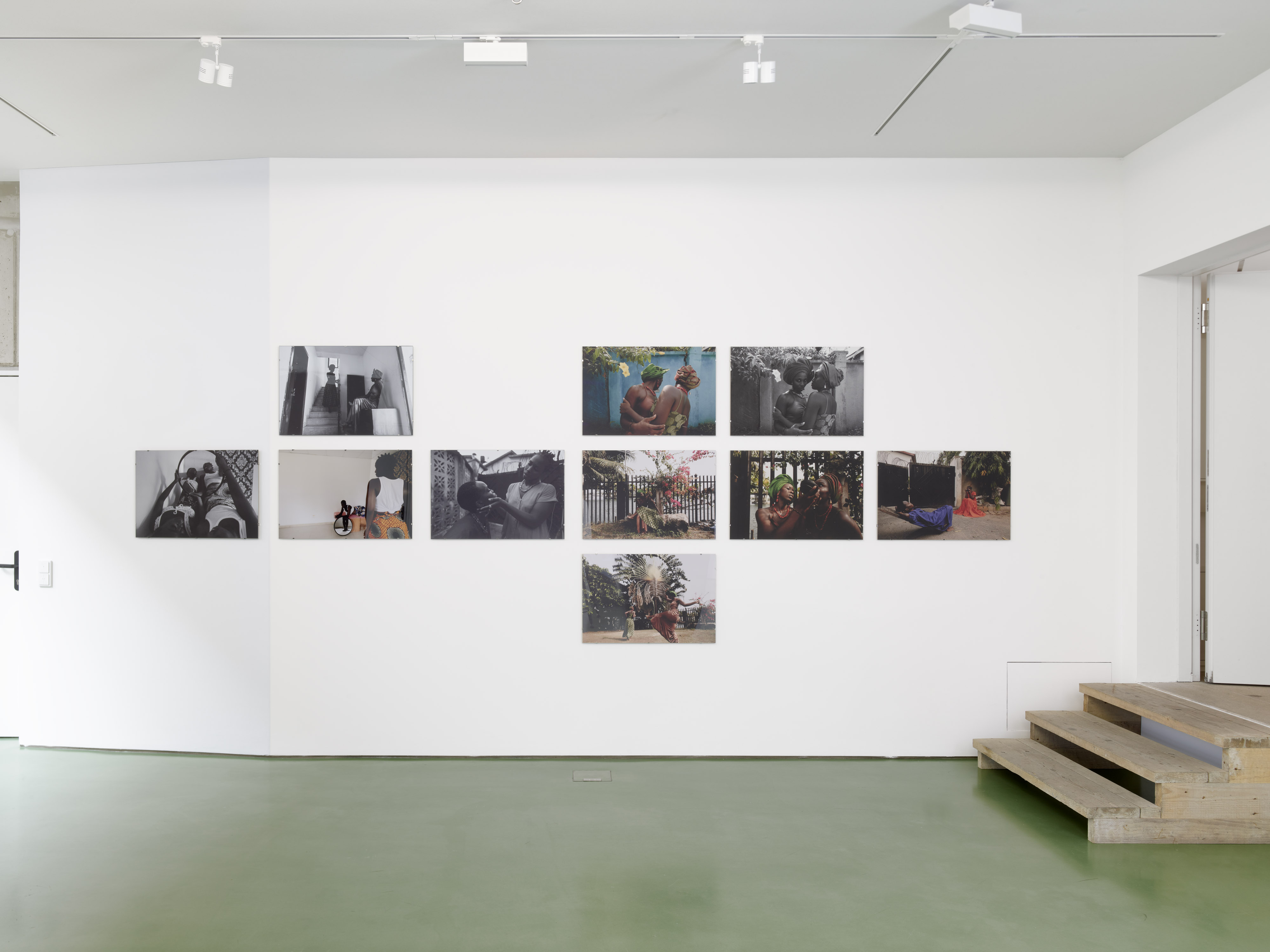 A gallery wall displaying various photographs in black and white and color, with images depicting people in different settings.