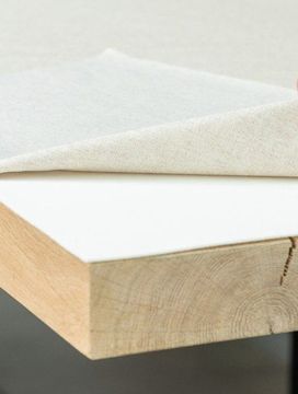 Tafelkleed wordt opgetild en toont een witte tafelmolton op een eiken tafel