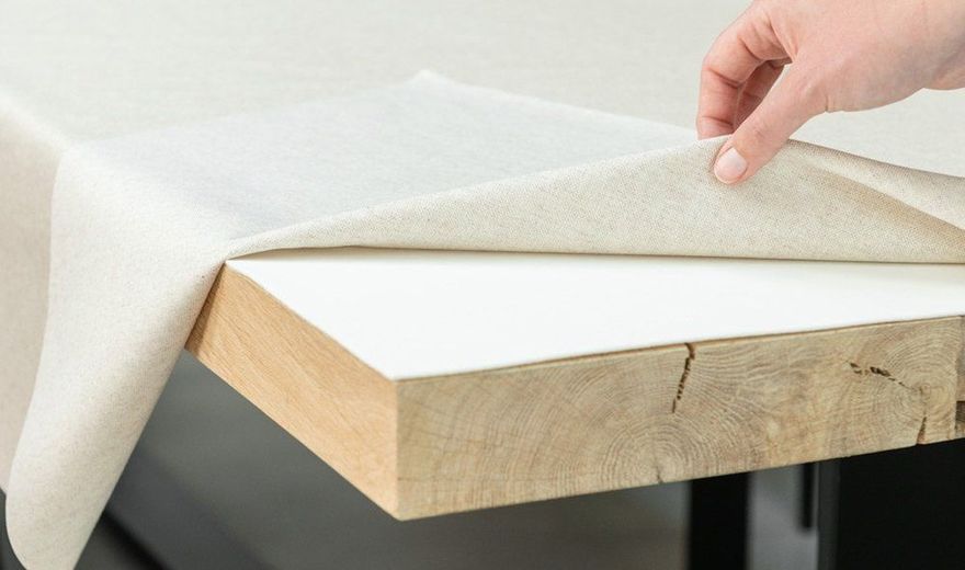 Tafelkleed wordt opgetild en toont een witte tafelmolton op een eiken tafel