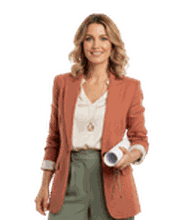 Woman in a salmon blazer holding rolled papers, smiling at the camera, wearing a white blouse, and gray pants.