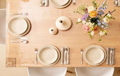 Elegant table setting with white plates, cutlery and flowers.