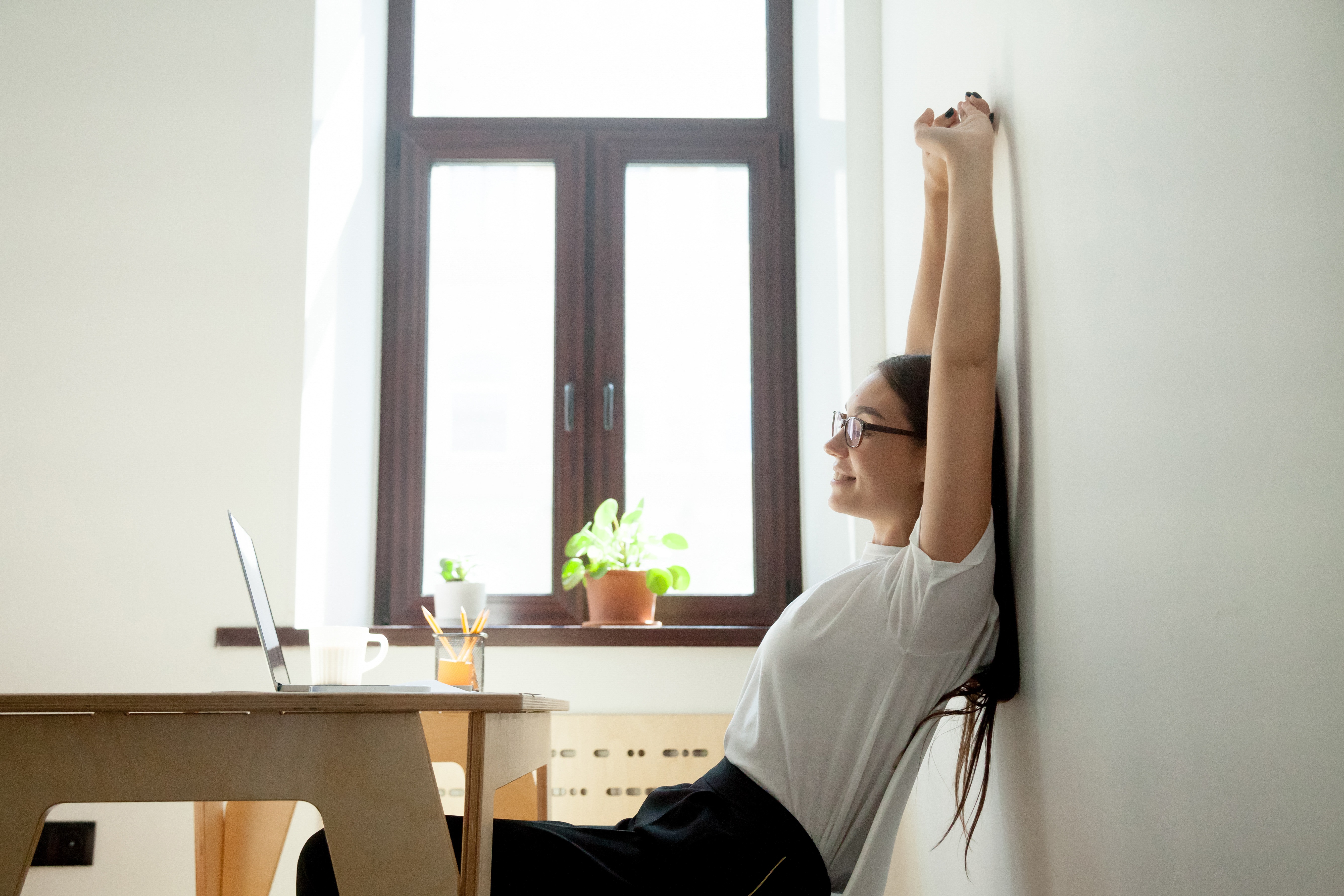 person_streching_on_chair_sitting_behind_laptop