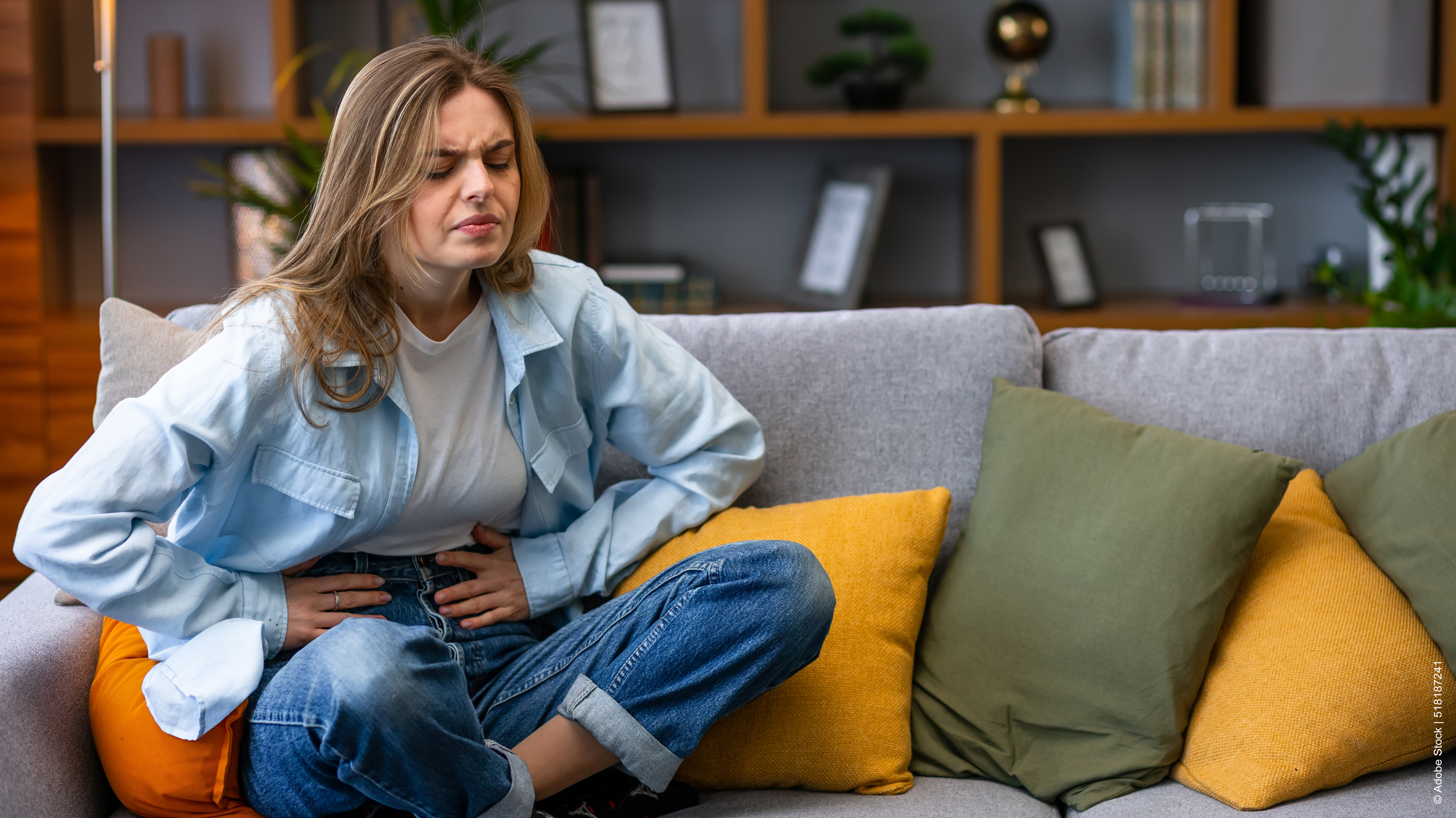Frau mit Bauchschmerzen sitzt auf der Couch
