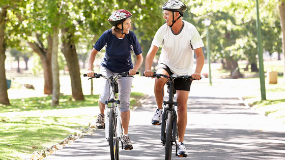Frau und Mann mit Helm beim Radfahren durch den Park