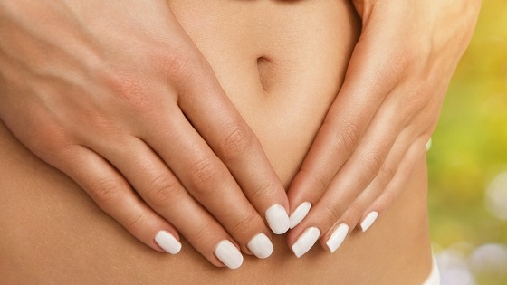 Frau hält Hände an Bauch