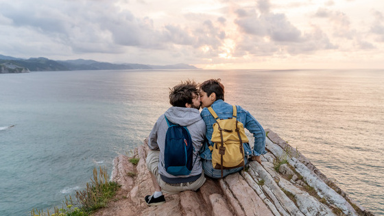 Zwei Personen auf einer Felsklippe mit Blick auf das Meer.