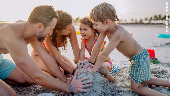Famlilie am Strand beim Sandburg bauen