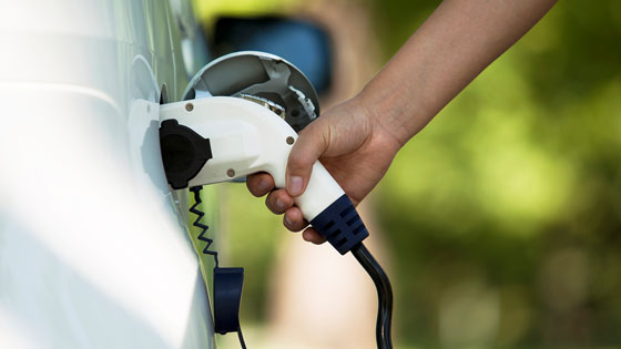 Jemand steckt einen E-Auto Ladestecker ins Elektroauto