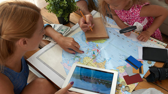Eine Frau zeigt einem Kind Destinationen auf einer Weltkarte.