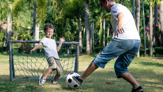 Vater und Sohn beim Freizeit-Fußballspielen auf einer grünen Wiese