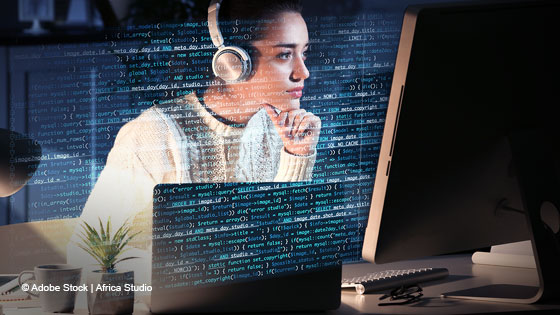 Frau sitzt mit Headset vor Computer