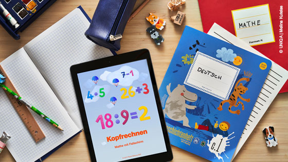 Schulsachen auf einem Tisch und ein Tablet mit einem Lernspiel.